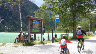 Avrupa, İtalya, Trentino Ağustos 2021 - Dolomites Catinaccio Dağlarında Lago di Carezza 'yı (Karersee Gölü) ziyaret eden turist - Yeşil berrak su ve çam ağacı