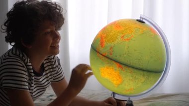 11 yaşında bir çocuk odasında, dünyaya bakıyor.