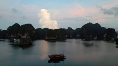 Dağlarla çevrili sakin sularda yüzen bir tekne.