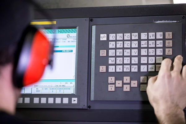 CNC exploitant, mechanische technicus werknemer op metalen machinale bewerking frezen center in hulpprogramma werkplaats invoegen van gegevens met toetsenbord dragen hoofdtelefoon met ruisonderdrukking — Stockfoto