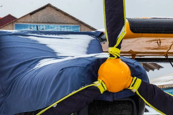 Parlak renklerle boyanmış pervaneli küçük bir uçak ya havaalanında ya da kışın karda havaalanında.