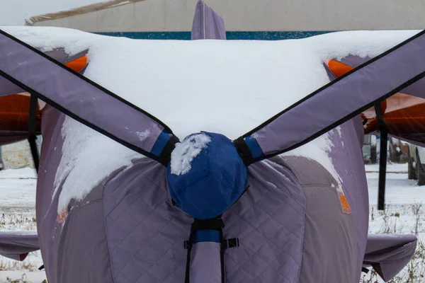 Parlak renklerle boyanmış pervaneli küçük bir uçak ya havaalanında ya da kışın karda havaalanında.