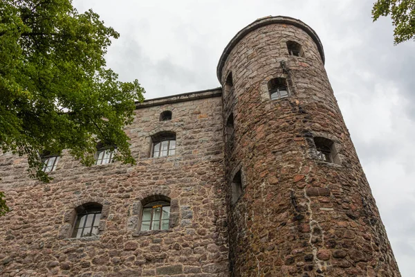 Taştan yapılmış bir kulesi olan ortaçağ şatosu, gökyüzüne karşı tuğla ve güzel bir yaz günü şehirde yeşil ağaçlar.