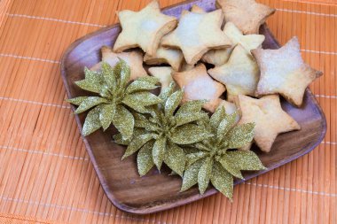 Ev yapımı lezzetli, tatlı Noel, yeni yıl kurabiyeleri ahşap tabakta altın süslemeler, evde turuncu bambu peçeteler.