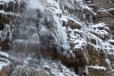 Dağlarda güzel kış manzaraları, ağaçlar, bitkiler, kayalar, şelaleler, sarkıtlar, soğuk havada düşen kar.