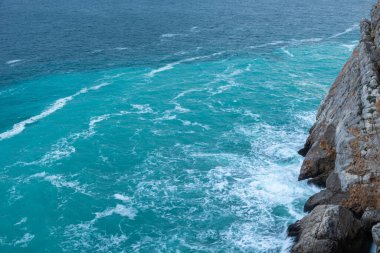 Fırtınada ve kayalarda büyük dalgalar olan güzel mavi deniz