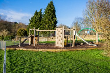 Bir çocuk parkında tahta bir tırmanma duvarı, köprü, rampalar, Bradford 'da Avon Wiltshire' da bir ağ ve metal kayması olan bir oyun ekipmanı.