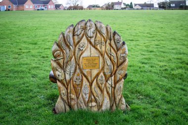 The back of a carved wooden memorial seat commemorating  a deceased village resident to recognise her work for the community clipart