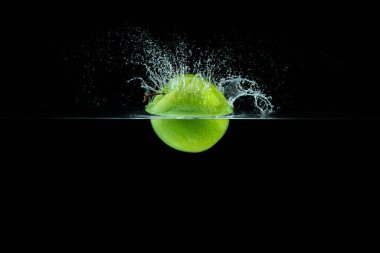 Yeşil elma su sıçrama ile siyah arka plan üzerine düşen.