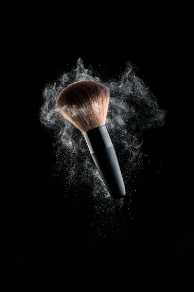 Close up powder splash and brush for makeup artist or beauty blogger in black background