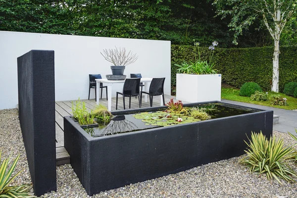 Garden with modern garden furniture and trendy pond.