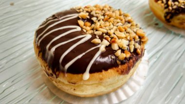 Ev yapımı çikolatalı çörekler. Çikolata, fındık ve bademle süslenmiş donut çikolata ve şeker ile süslenmiş. Yaratıcılık, leziz doku ve lezzet dolu garnitür.