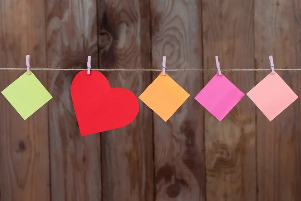 Colored pieces of paper and heart hanging on a rope — Stock Photo, Image
