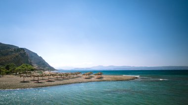 Yunanistan'da bir kum plajındaki saman şemsiye. 