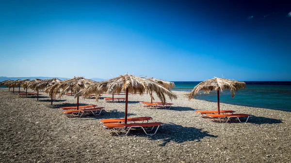 Guarda-chuva de palha em uma praia de areia na Grécia . — Fotografia de Stock