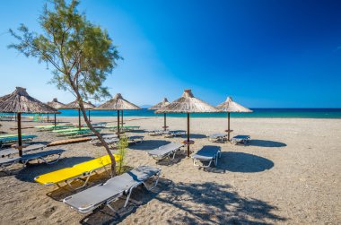 Yunanistan'da bir kum plajındaki saman şemsiye. 