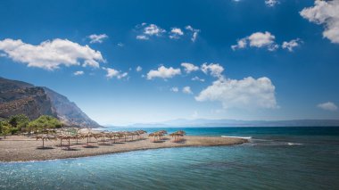Yunanistan'da bir kum plajındaki saman şemsiye. 