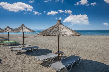 Yunanistan'da bir kum plajındaki saman şemsiye. 