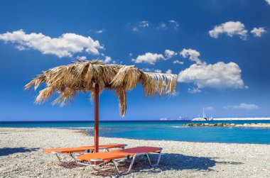 Yunanistan'da bir kum plajındaki saman şemsiye. 