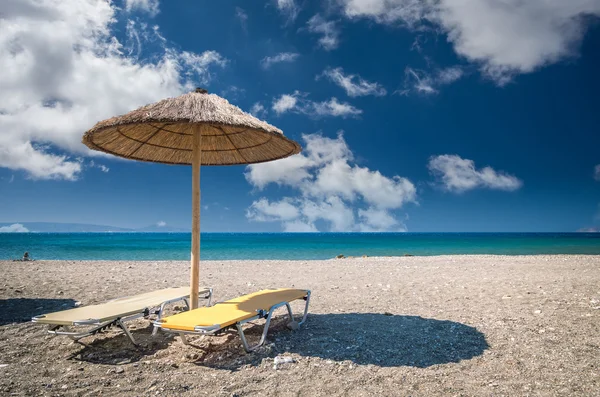 Straw umbrella on a sandy beach in Greece. — Stock Photo, Image