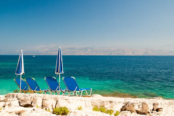 Leżaki i parasole (parasole) na kamienistej plaży w wyspa Korfu, Grecja — Zdjęcie stockowe
