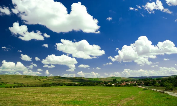 Campo verde y cielo azul con nubes claras — Foto de Stock