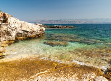 Kayalık Kassiopi Beach, Corfu Island, Yunanistan. Şezlong ve şemsiye