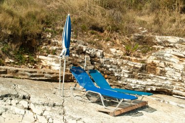 Şezlong ve şemsiye (şemsiye) sahilde Korfu Adası