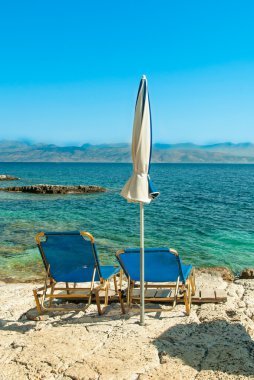 Şezlong ve şemsiye (şemsiye) sahilde Korfu Adası