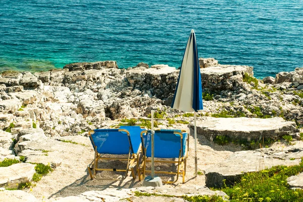 Lettini e ombrelloni (ombrelloni) sulla spiaggia dell'isola di Corfù — Foto Stock