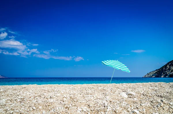 Beach umbrella on sunny Myrtos beach, the ionian sea in backgrou — Stock Photo, Image