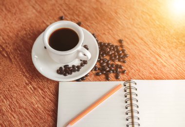 Kahve fincanı ve çay tabağı ahşap bir masada. Koyu arkaplan.