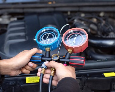 Servis teknisyenleri otomatik araba klimasının basıncını ölçüyorlar..