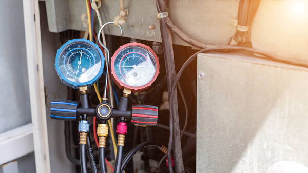 Механик по ремонту воздуха с помощью измерительного оборудования для заполнения промышленных кондиционеров воздуха завода и проверки технического обслуживания компрессорного агрегата наружного воздуха.