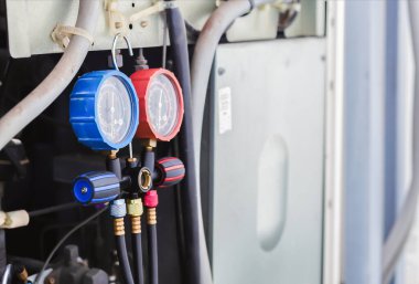 Hava tamircisi endüstriyel klimaları doldurmak için ölçüm aletleri kullanıyor..