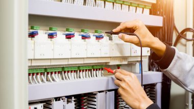 Elektrik mühendisi elektrik kontrol kabinesinin bakımını düzenli olarak test ediyor.