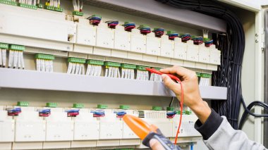 Elektrik mühendisi elektrik kontrol kabinesinin bakımını düzenli olarak test ediyor.