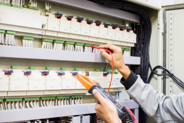 Elektrik mühendisi elektrik kontrol kabinesinin bakımını düzenli olarak test ediyor.