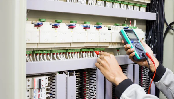 Elektrik mühendisi elektrik kontrol kabinesinin bakımını düzenli olarak test ediyor.