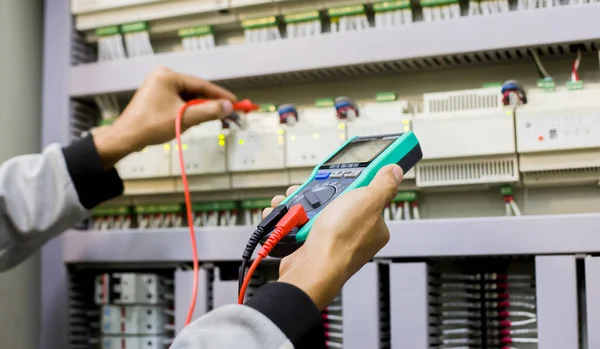 Electrical engineer tests the operation of the electric control cabinet on a regular basis for maintenance.