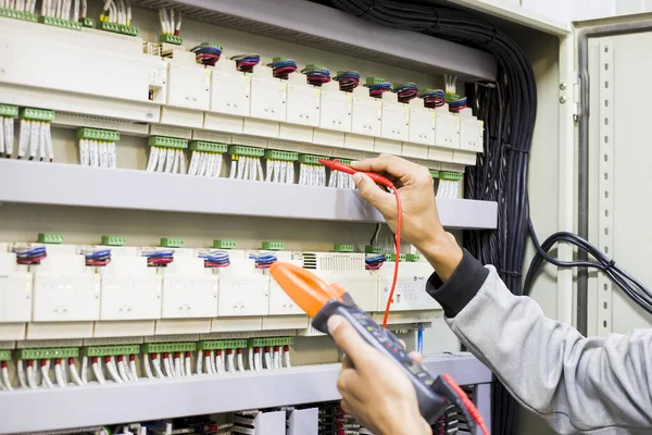 Electrical engineer tests the operation of the electric control cabinet on a regular basis for maintenance.