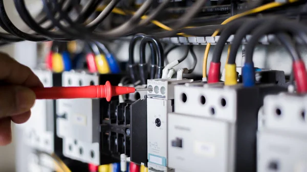 Elektrik mühendisi elektrik kontrol kabinesinin bakımını düzenli olarak test ediyor.