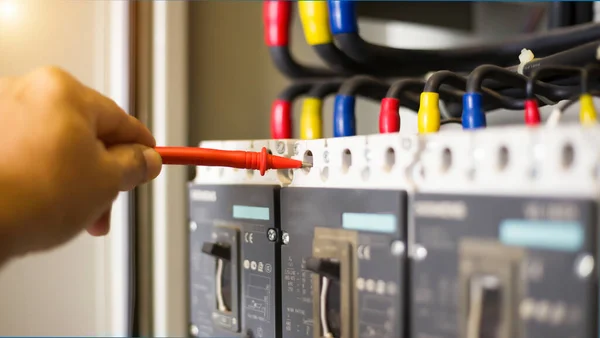 Electrical engineer tests the operation of the electric control cabinet on a regular basis for maintenance.