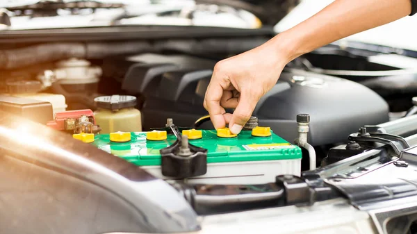 Bir teknisyen araba aküsünün damıtılmış su seviyesini kontrol ediyor..