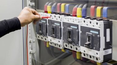 Elektrik mühendisi elektrik kontrol kabinesinin bakımını düzenli olarak test ediyor.