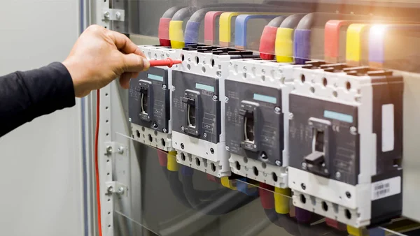 Electrical engineer tests the operation of the electric control cabinet on a regular basis for maintenance.