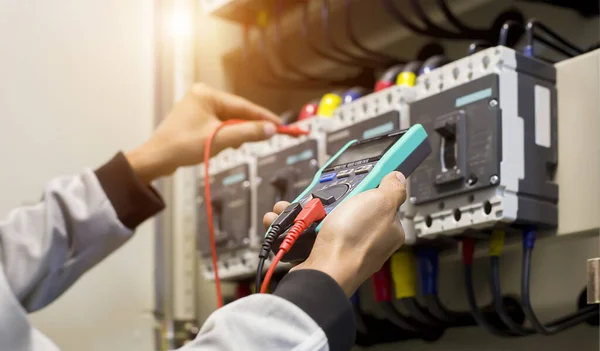 Electrical engineer tests the operation of the electric control cabinet on a regular basis for maintenance.