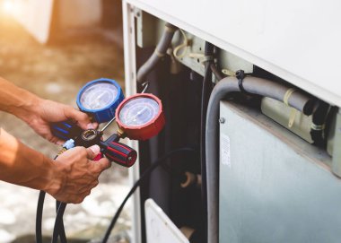 Hava tamircisi endüstriyel klimaları doldurmak için ölçüm aletleri kullanıyor..