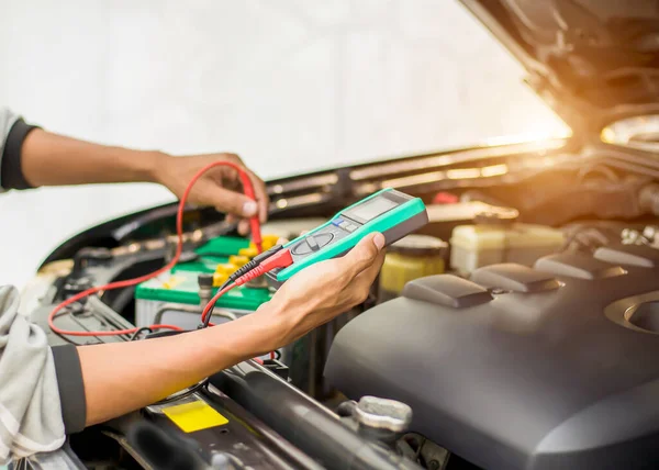 Bir teknisyen araba aküsünü kontrol ediyor..;