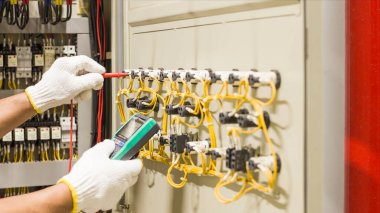 Elektrik mühendisi elektrik kontrol kabinesinin bakımını düzenli olarak test ediyor.